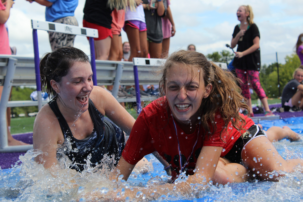 During a break in Freshmen Field Day, seniors Bridget Koeppen and Abby Englert slide into rainwater left on a tarp covering the long jump sand pit. An annual back to school tradition, freshman and seniors participated in a variety of activites, including Pound, tug of war and chalk drawing.