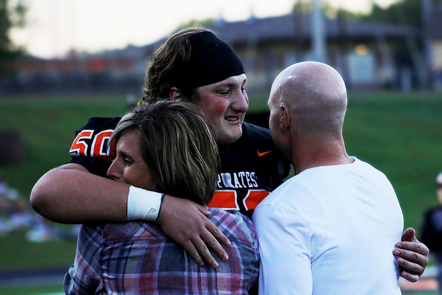 Embraced in a hug, senior Glen Gammill meets his parents on the track during senior night on Oct. 19 before the Blackout game. Upon seeing his parents, Gammill began to cry. Now I realize that having them there for me has pushed me a lot and Im thankful for that, Gammill said. Not only has their motivation pushed me on the field, but it has shaped me into the person I am today.