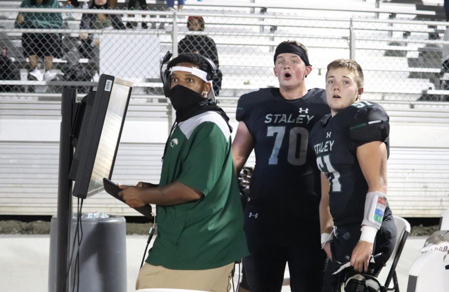 On the sidelines, juniors Zachary Sherwood, Anderson Hendershot and coach Jared Simmons watch the play. Varsity defense was able to make an important play and stop the opponents from making a first down Oct. 9, winning 45-6 against Oak Park High School. "I felt excited and a bit worried that it wasn't going to go right, but after the play I was extremely excited because our defense made the stop," said Sherwood. 