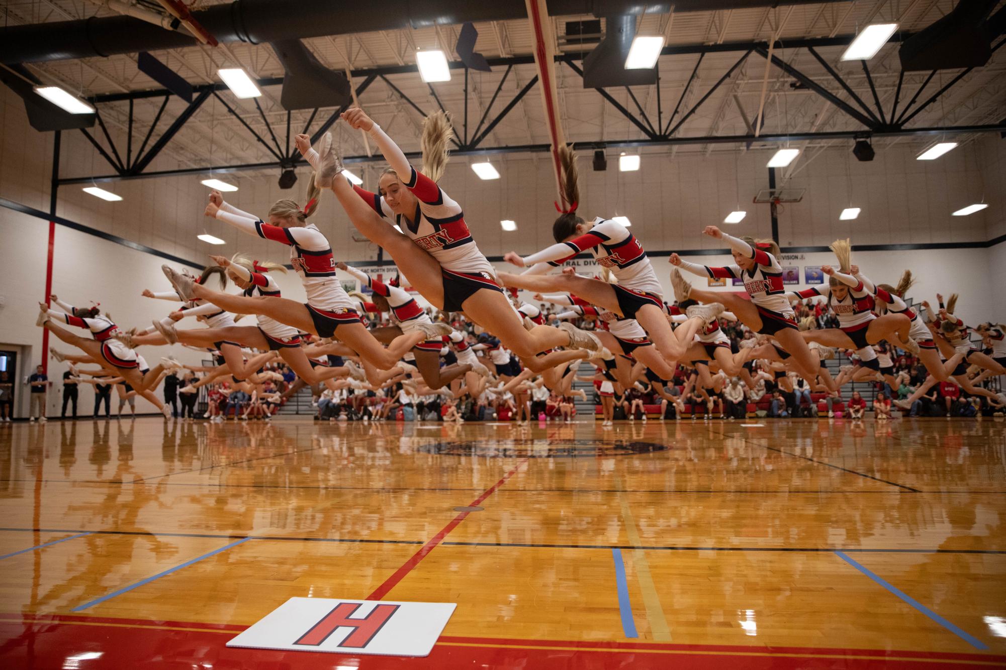 Varsity cheer team members jump in unison during their routine during the homecoming pep assembly on Oct. 16. Cheer helped to kick off the assembly festivities, which also featured the homecoming court and spirit king and queen. "The energy at assemblies is just a good feeling and makes you excited and want to be there," cheerleader Austin Koehnemann (12) said. "The music, the people all help just make the energy and vibes good."