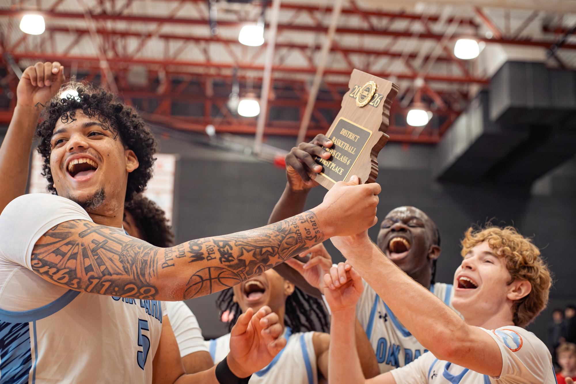 Seniors Landon VanPelt, Joshua Kori, and Adam Tanner hold up the class 6, district 8 championship plaque in celebration of their third consecutive championship win to return to the state tournament on Saturday, March 7.